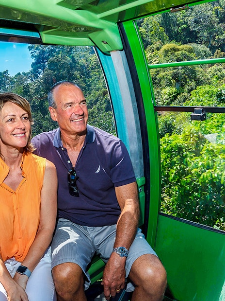 Couple enjoying the view from Kuranda Skyrail Cableway over lush rainforest and coastline.