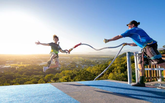 Visitor bungee jumping from Skypark Cairns roof at sunrise.