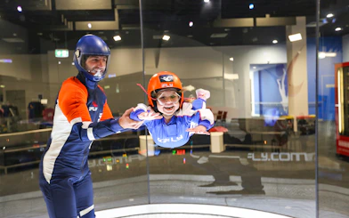 Child experiencing indoor skydiving with instructor at iFly Sydney.