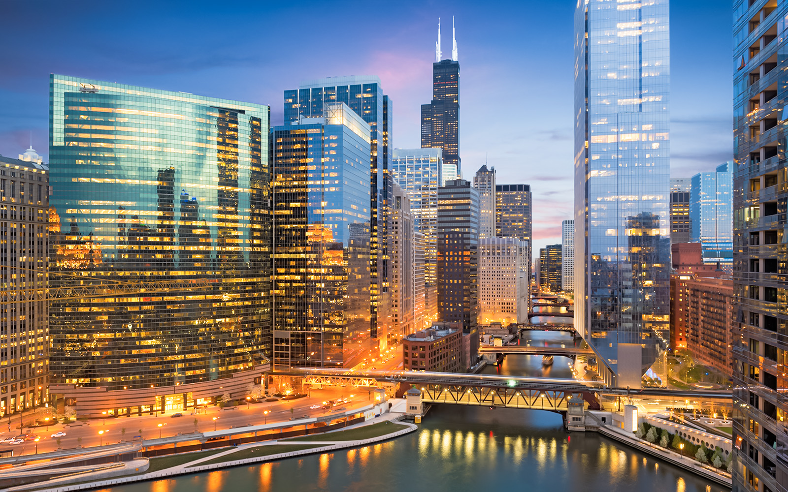 Chicago skyline with illuminated skyscrapers and river at dusk, Illinois, USA.
