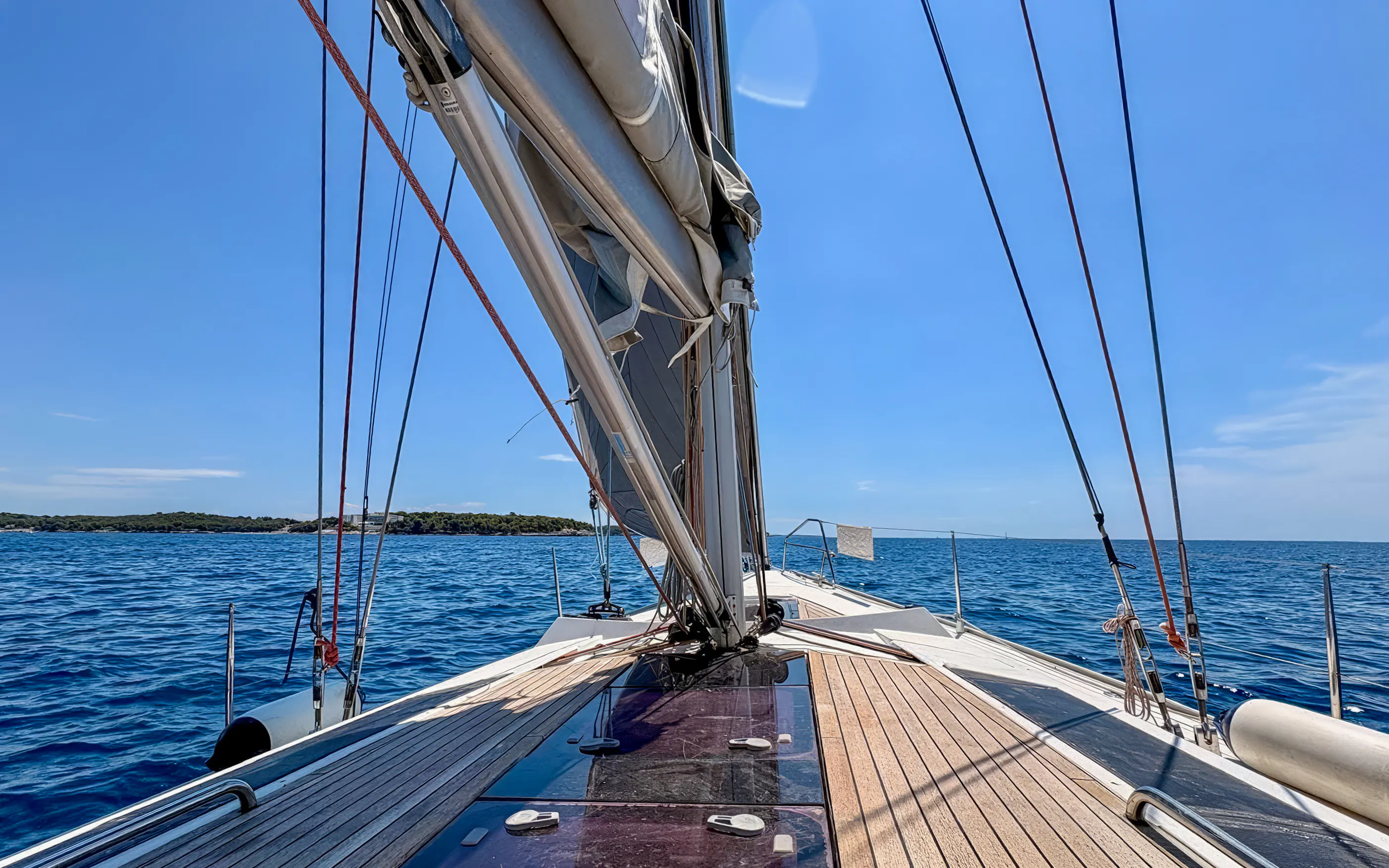 Sailing boat deck on Adriatic Sea near Pula, Croatia, under clear blue sky.