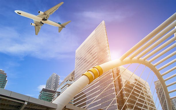 Airplane flying over Bangkok skyline with modern architecture.