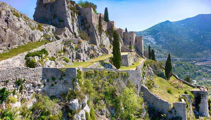Klis Fortress stone walls and towers on a hillside in Croatia.