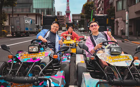 Go-kart riders in costumes on Tokyo street with Tokyo Tower in background.