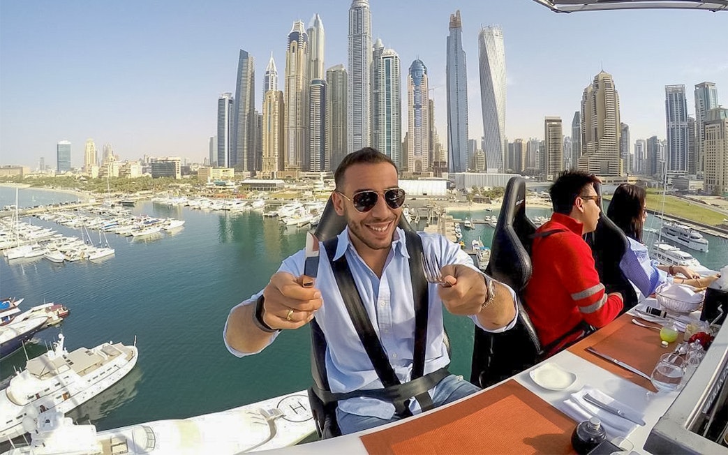 Dining experience suspended above Dubai Marina with city skyline in view.
