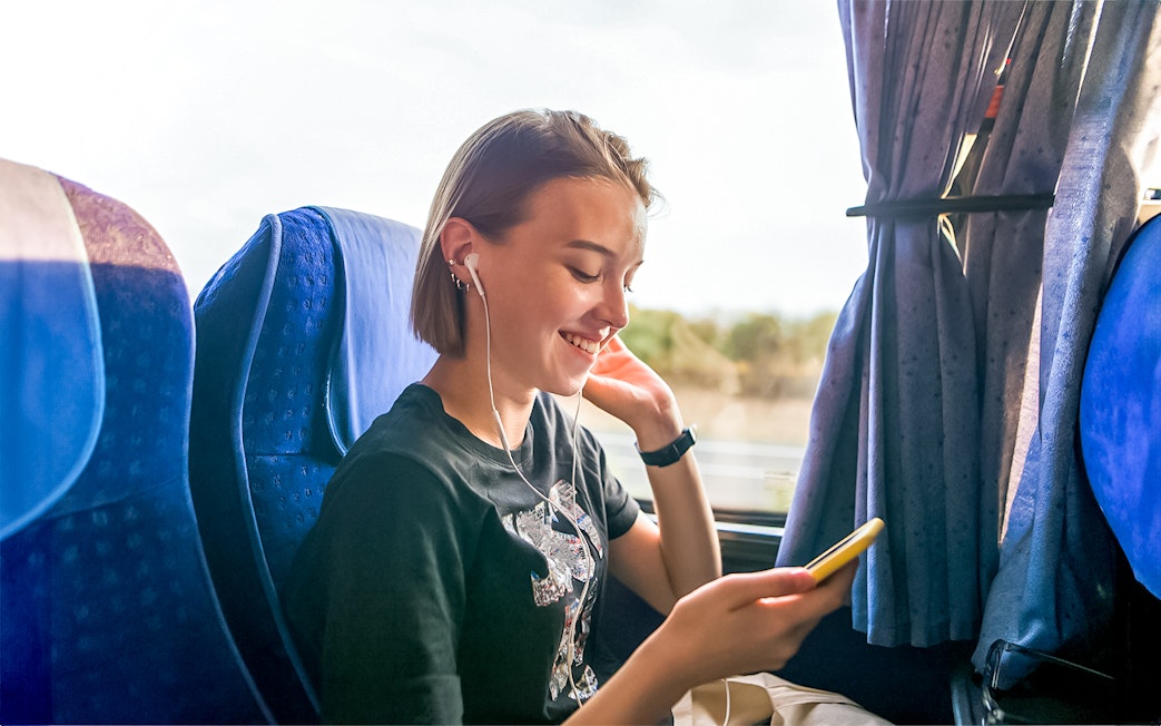 Traveler enjoying music on a coach transfer during a day trip.
