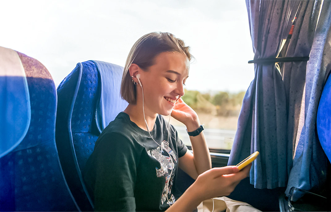 Traveler enjoying music on a coach transfer during a day trip.
