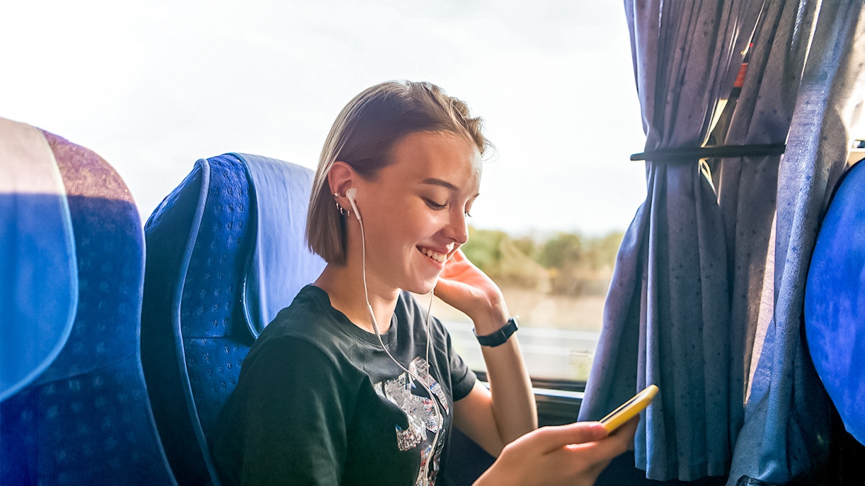Traveler enjoying music on a coach transfer during a day trip.