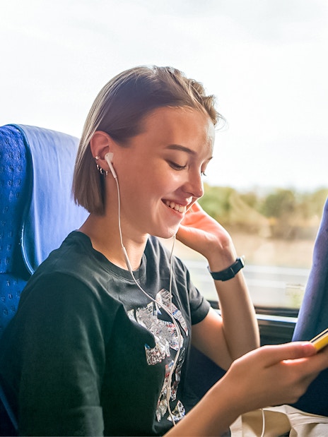 Traveler enjoying music on a coach transfer during a day trip.