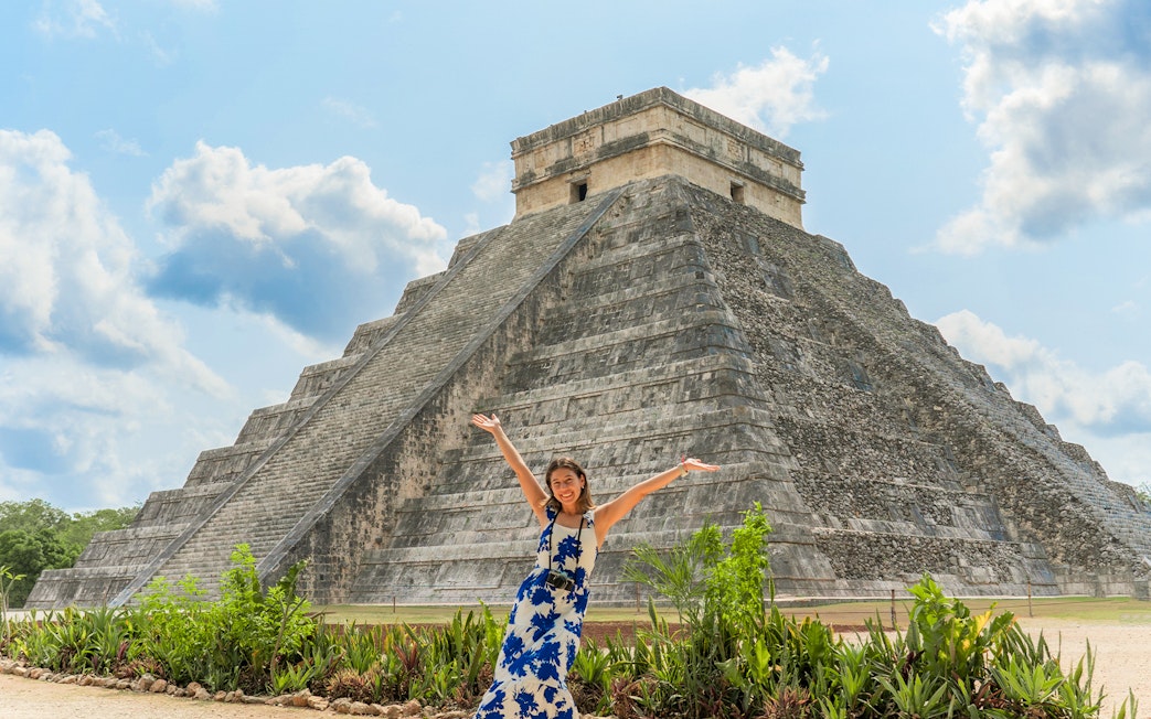 Woman posing in front of Chichen Itza pyramid during her tour in Mexico.