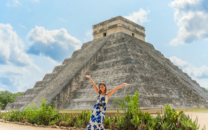 Woman posing in front of Chichen Itza pyramid during her tour in Mexico.