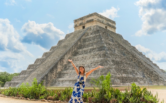 Woman posing in front of Chichen Itza pyramid during her tour in Mexico.