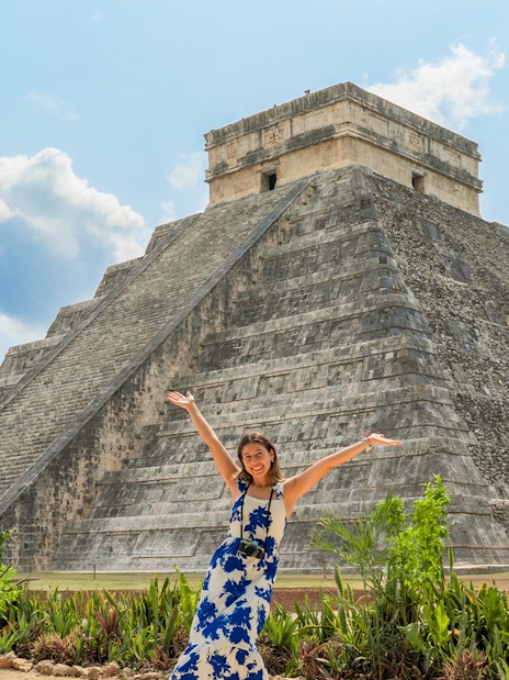 Woman posing in front of Chichen Itza pyramid during her tour in Mexico.