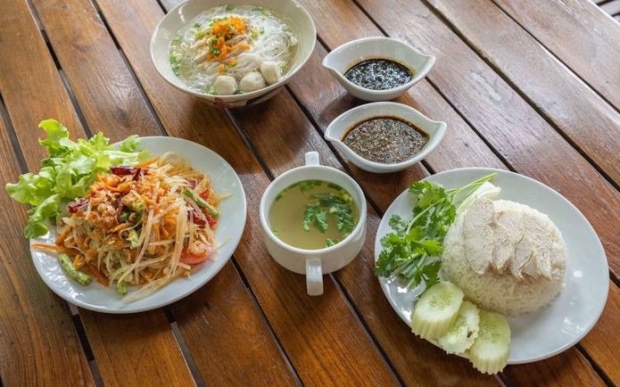 Traditional Thai dishes at Hanuman World buffet, featuring papaya salad, noodle soup, and chicken rice.