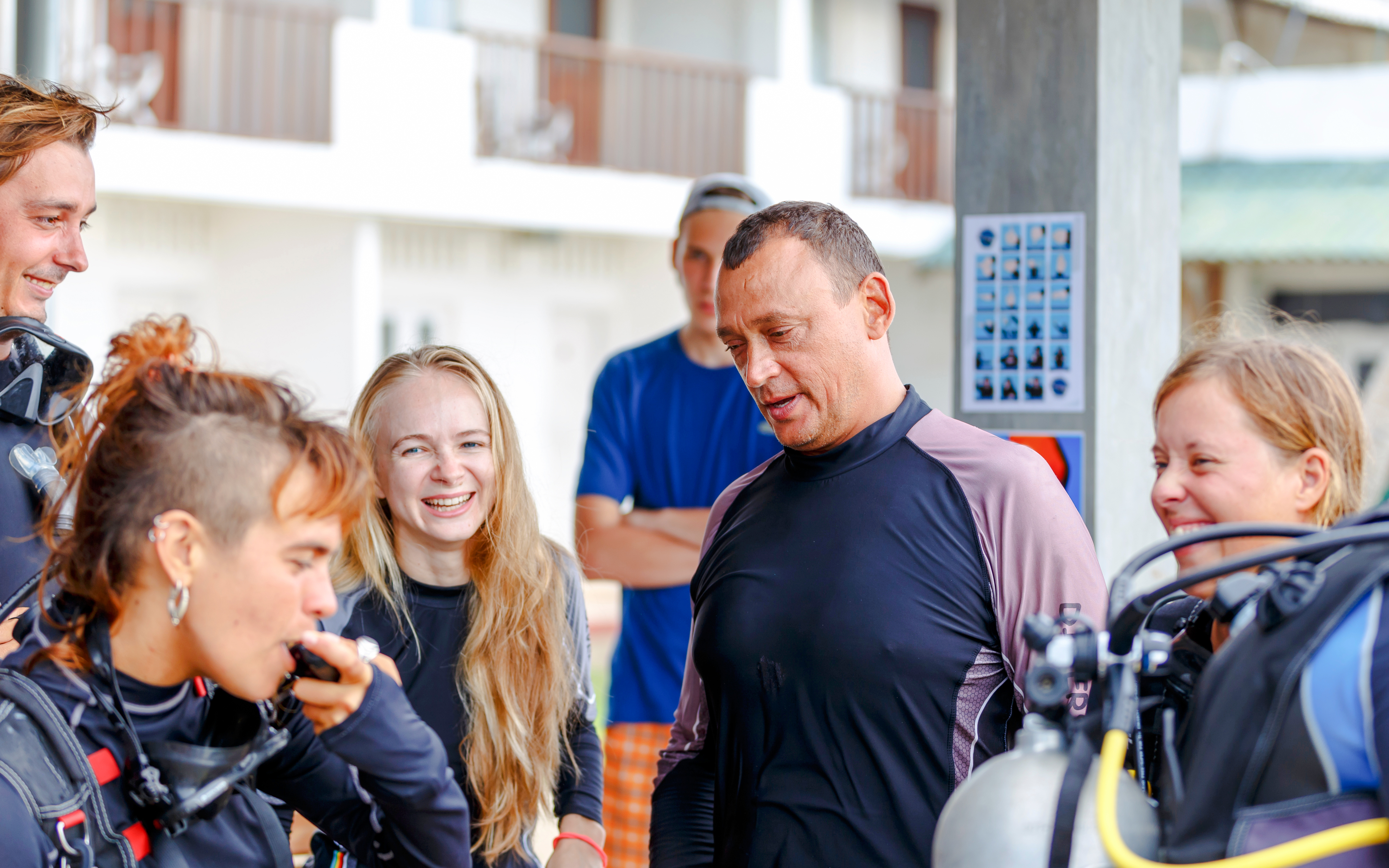 Scuba divers on a beach receiving pre-dive instructions.