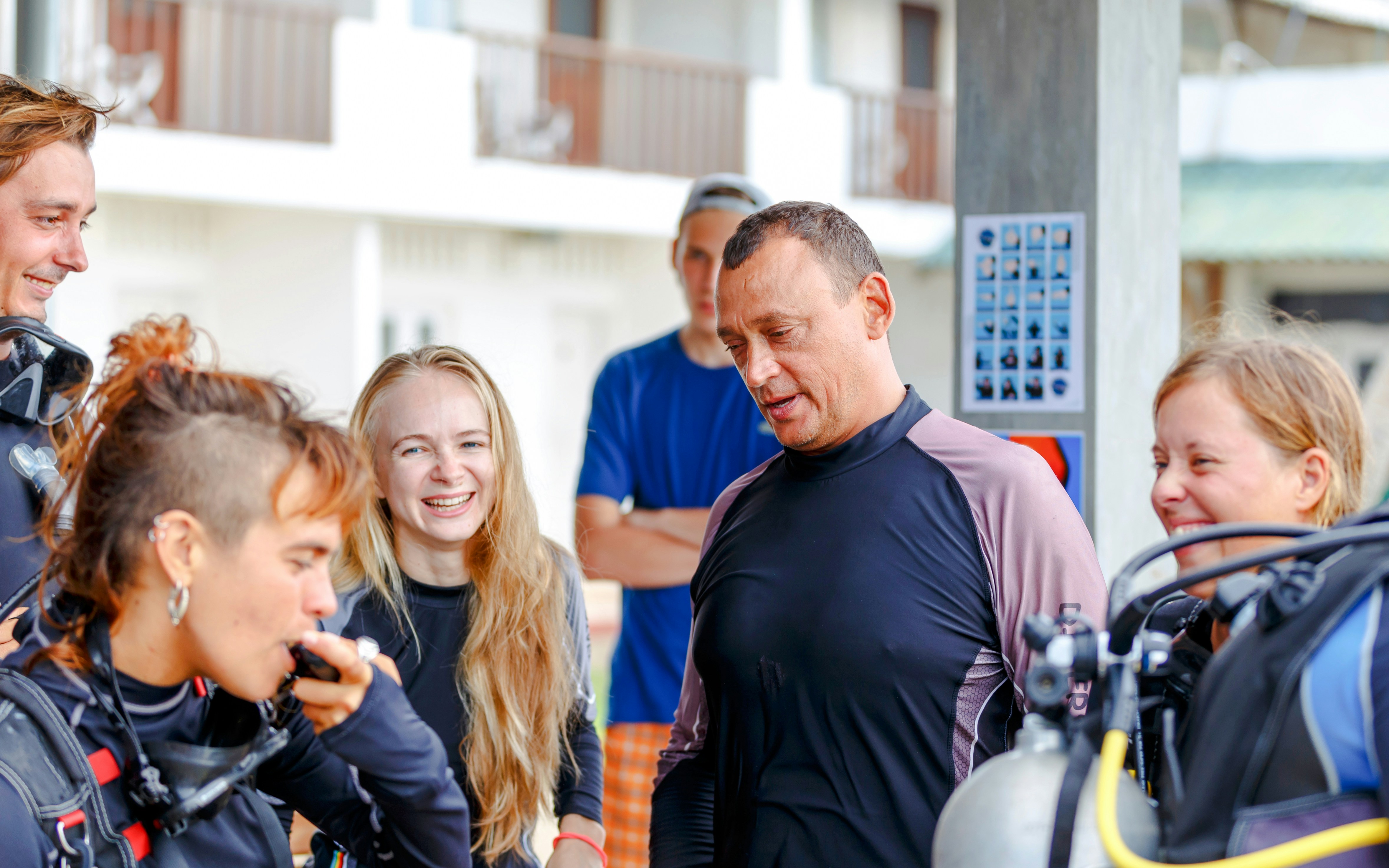 Scuba divers on a beach receiving pre-dive instructions.