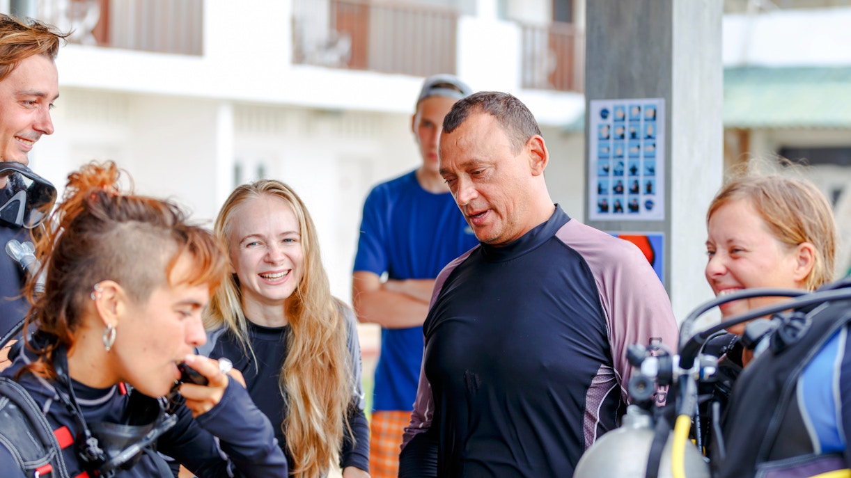 Scuba divers on a beach receiving pre-dive instructions.
