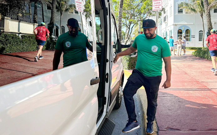 Guest entering a tour van on a sunny street.