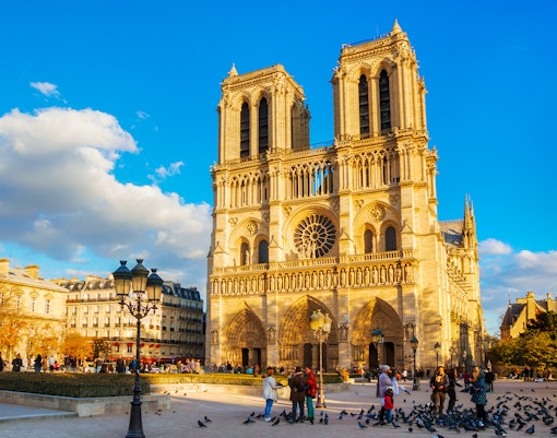 Notre Dame de Paris cathedral at sunset with warm golden hour light.