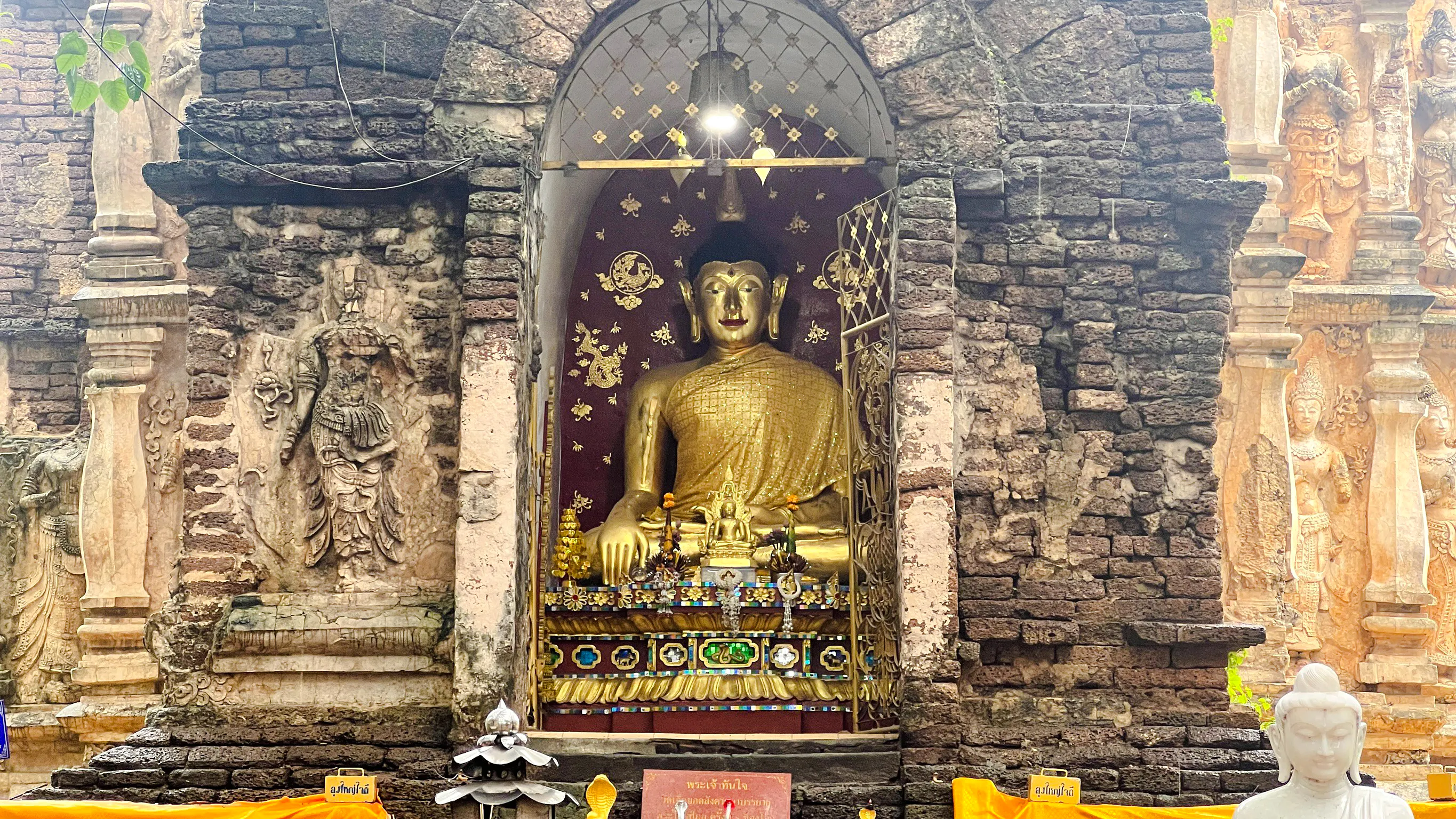 Golden Buddha statue in ancient temple niche, Chiang Mai.