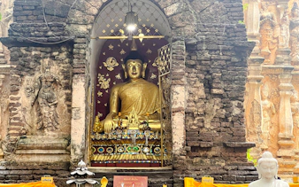 Golden Buddha statue in ancient temple niche, Chiang Mai.