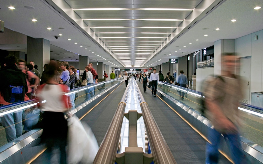 Passengers on a moving walkway at Narita Airport terminal.