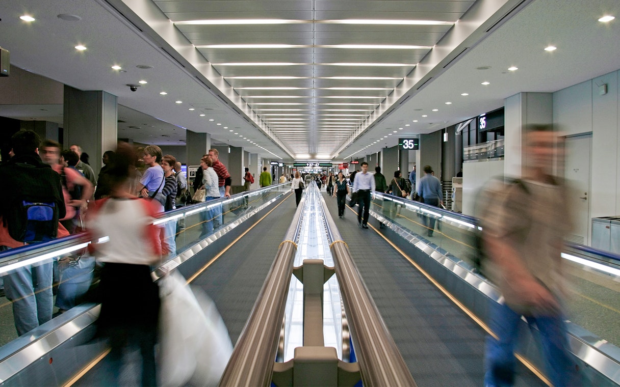 Passengers on a moving walkway at Narita Airport terminal.