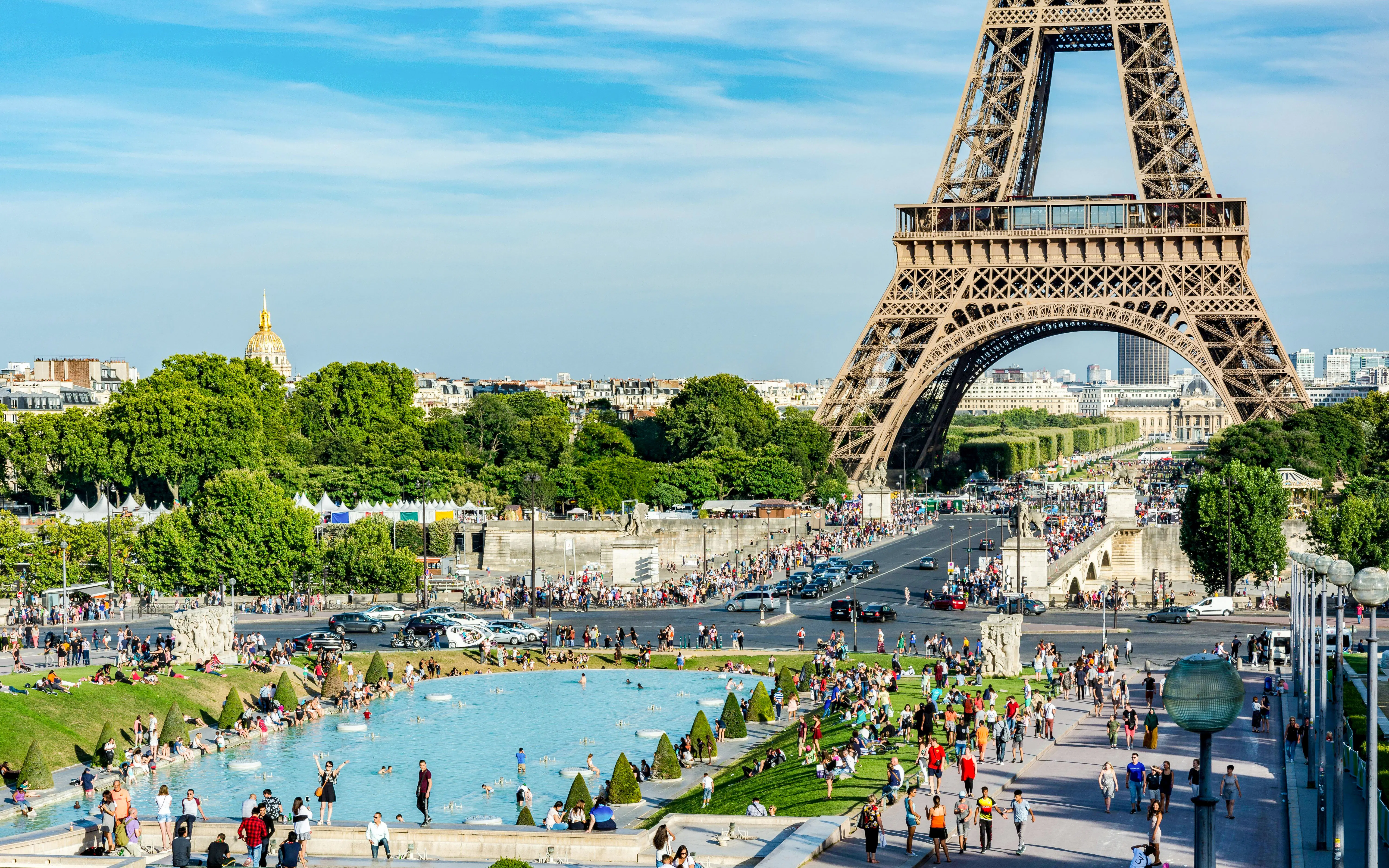 Visitors enjoying the park and fountain at Champ de Mars with the Eiffel Tower in the background.
