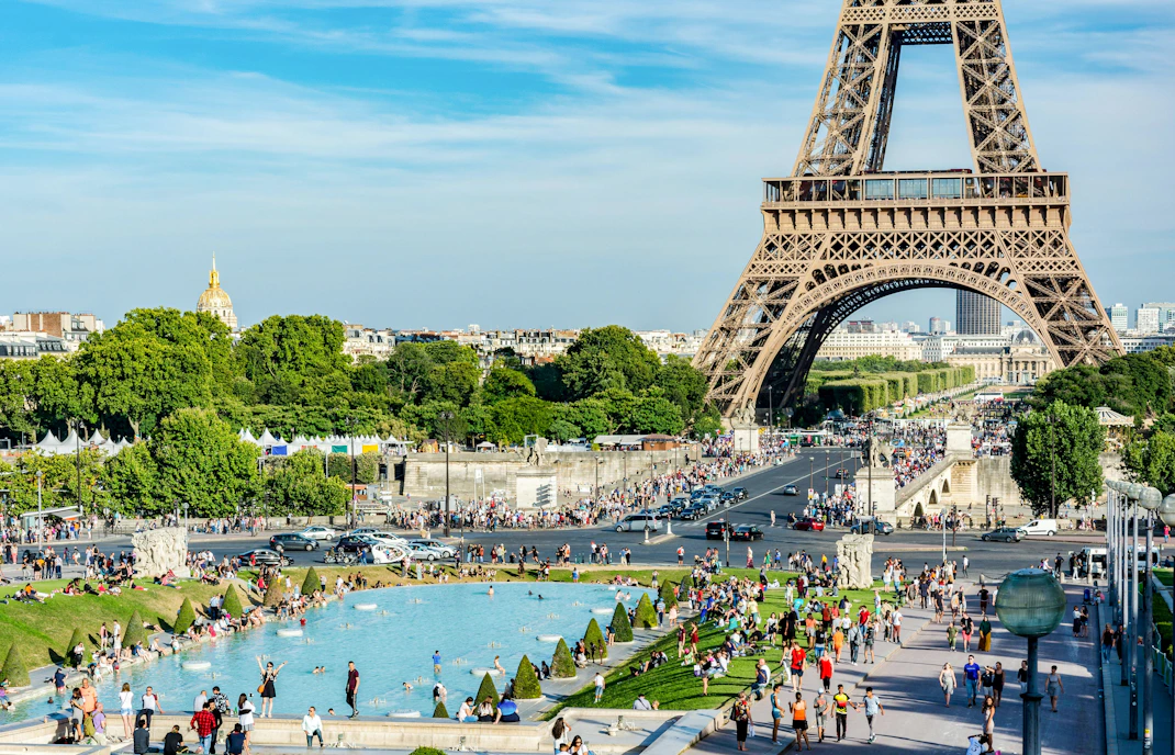 Visitors enjoying the park and fountain at Champ de Mars with the Eiffel Tower in the background.
