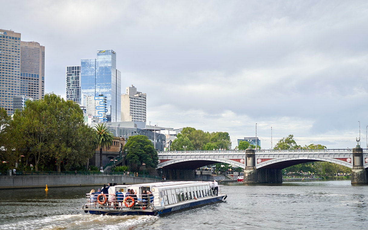Cruise boat on Yarra River passing under a bridge in Melbourne, Australia.