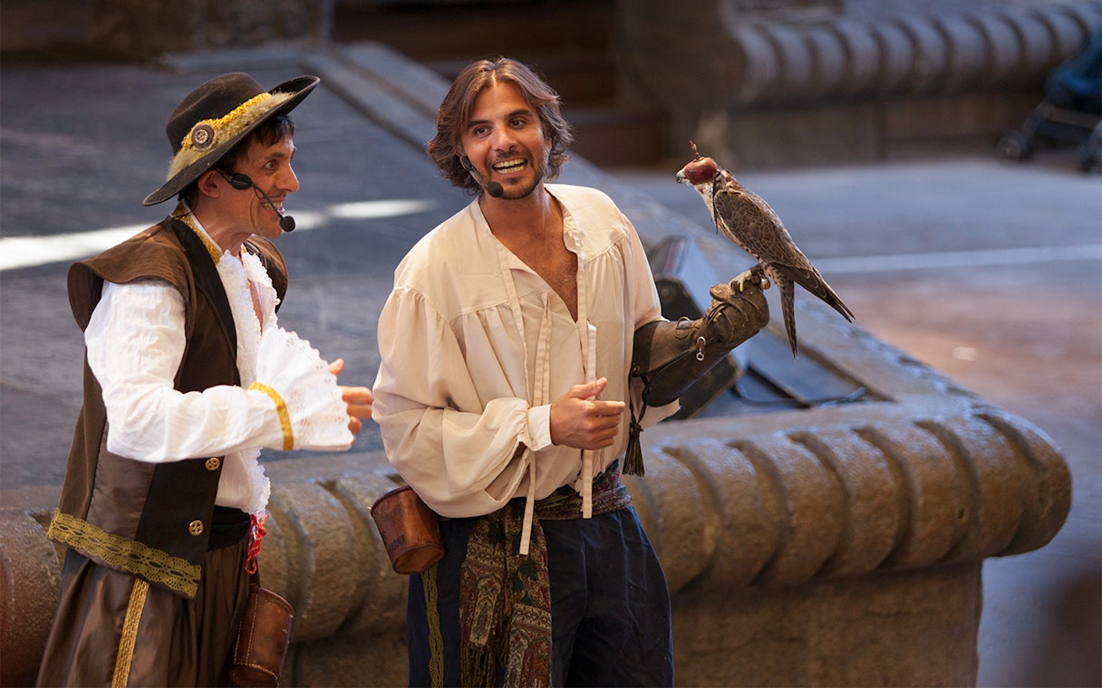 Falconry show at Isla Mágica with performers in period costumes.