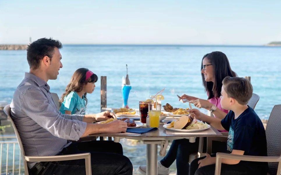 Family dining at Marineland Mallorca cafe with ocean view.