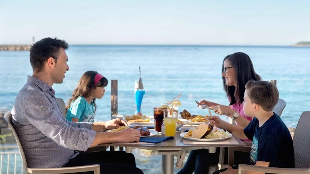 Family dining at Marineland Mallorca cafe with ocean view.
