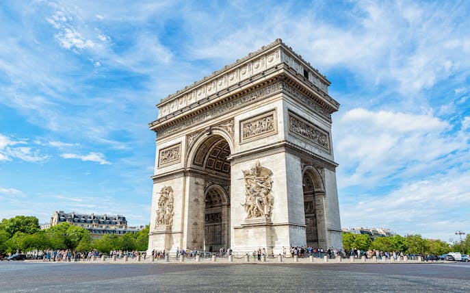Arc de Triomphe in Paris with tourists and clear blue sky.