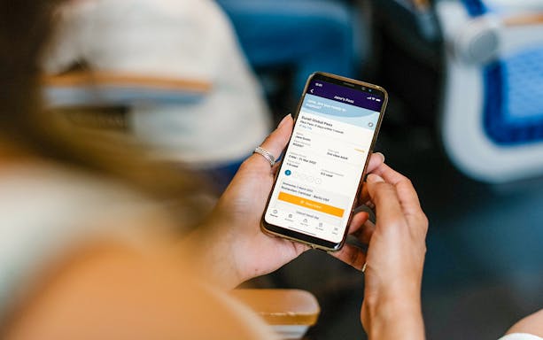 Person holding a smartphone displaying Eurail Global Mobile Pass Flex details.