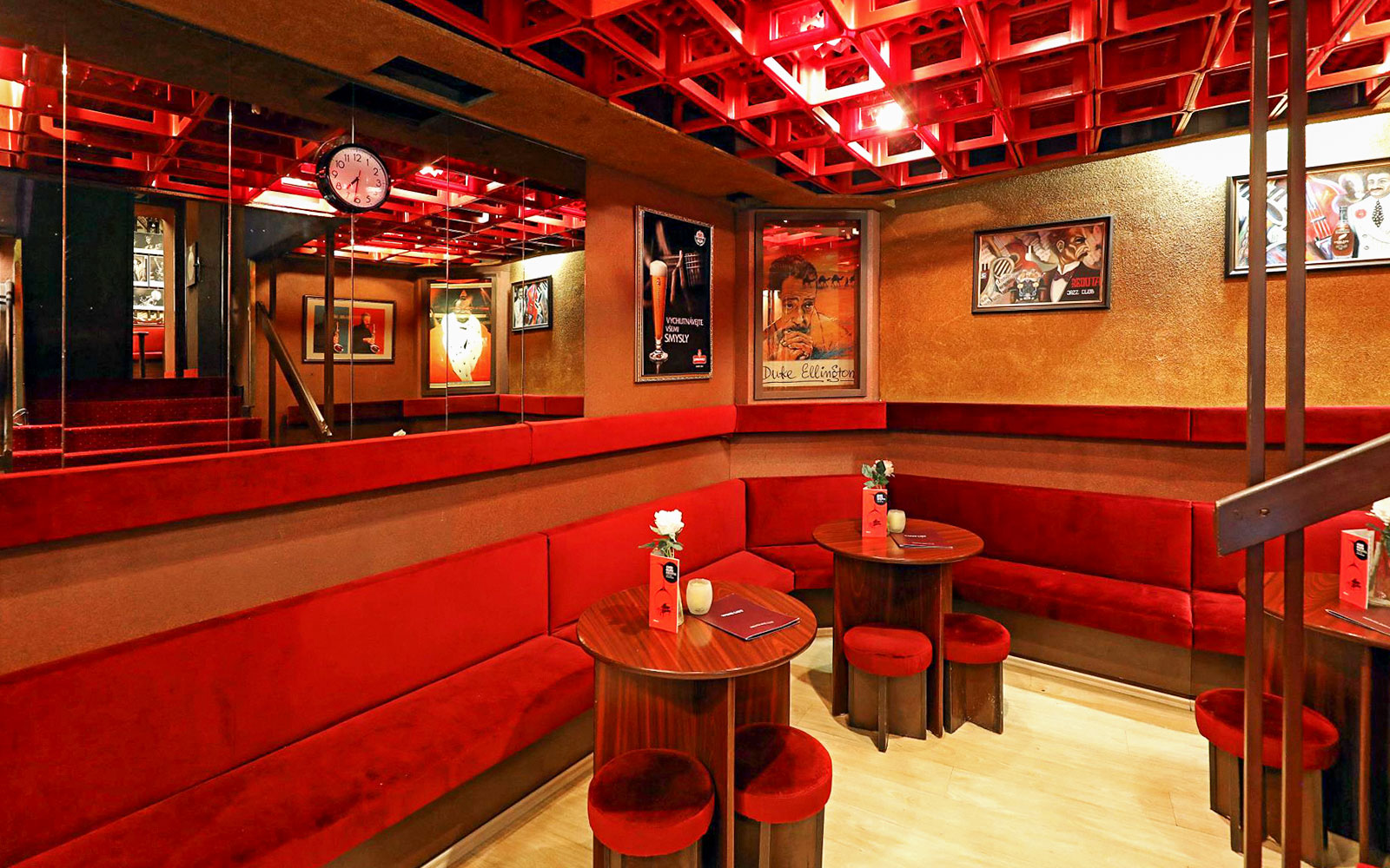 Interior seating area at Reduta Jazz Club with red velvet benches and jazz posters.