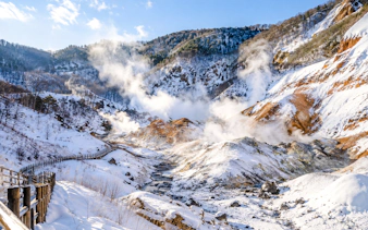 Noboribetsu's snow-covered geothermal valley with steam rising, Hokkaido winter tour.