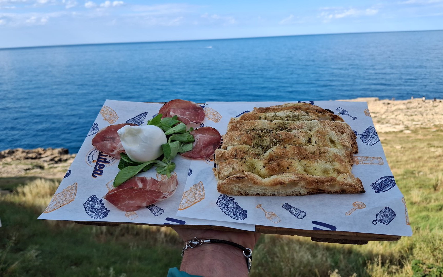 Focaccia bread with local cheese and cured meats by the sea during Polignano a Mare street food tour.