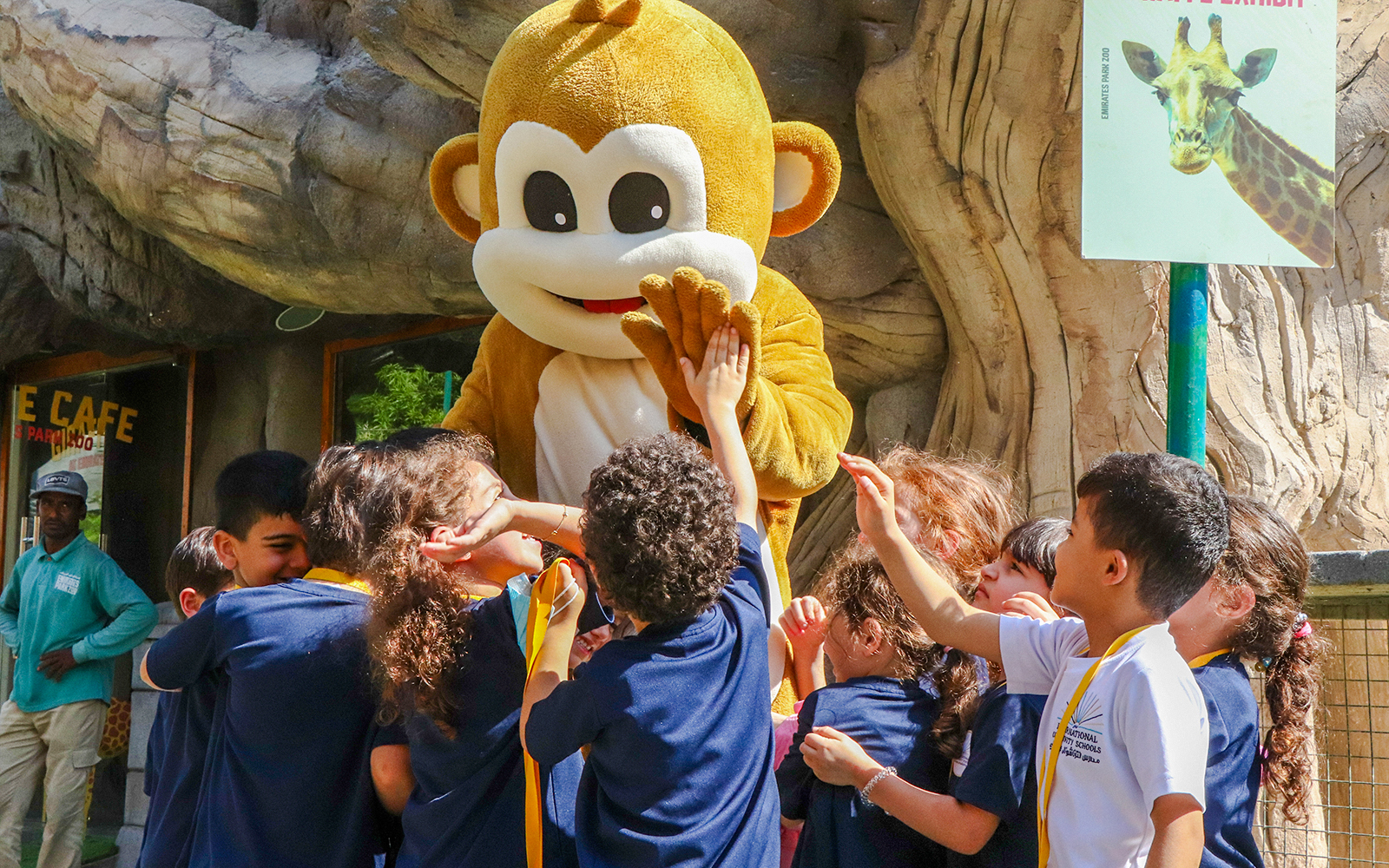 Children interacting with a monkey mascot at a zoo exhibit.