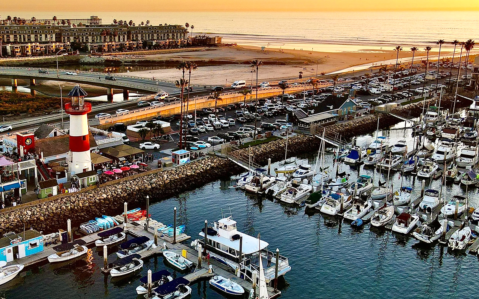 Marina with boats and lighthouse at sunset, San Diego, for luxury whale watching tour.