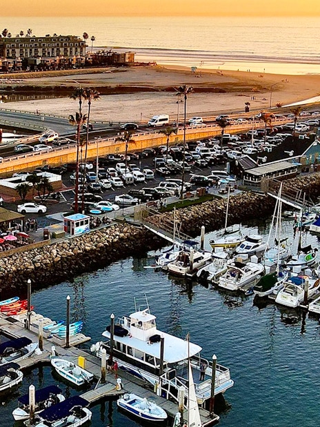 Marina with boats and lighthouse at sunset, San Diego, for luxury whale watching tour.