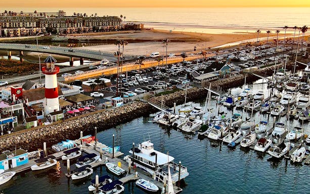 Marina with boats and lighthouse at sunset, San Diego, for luxury whale watching tour.