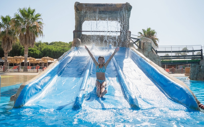 Child enjoying a water slide at Aquopolis Costa Daurada, Tarragona.