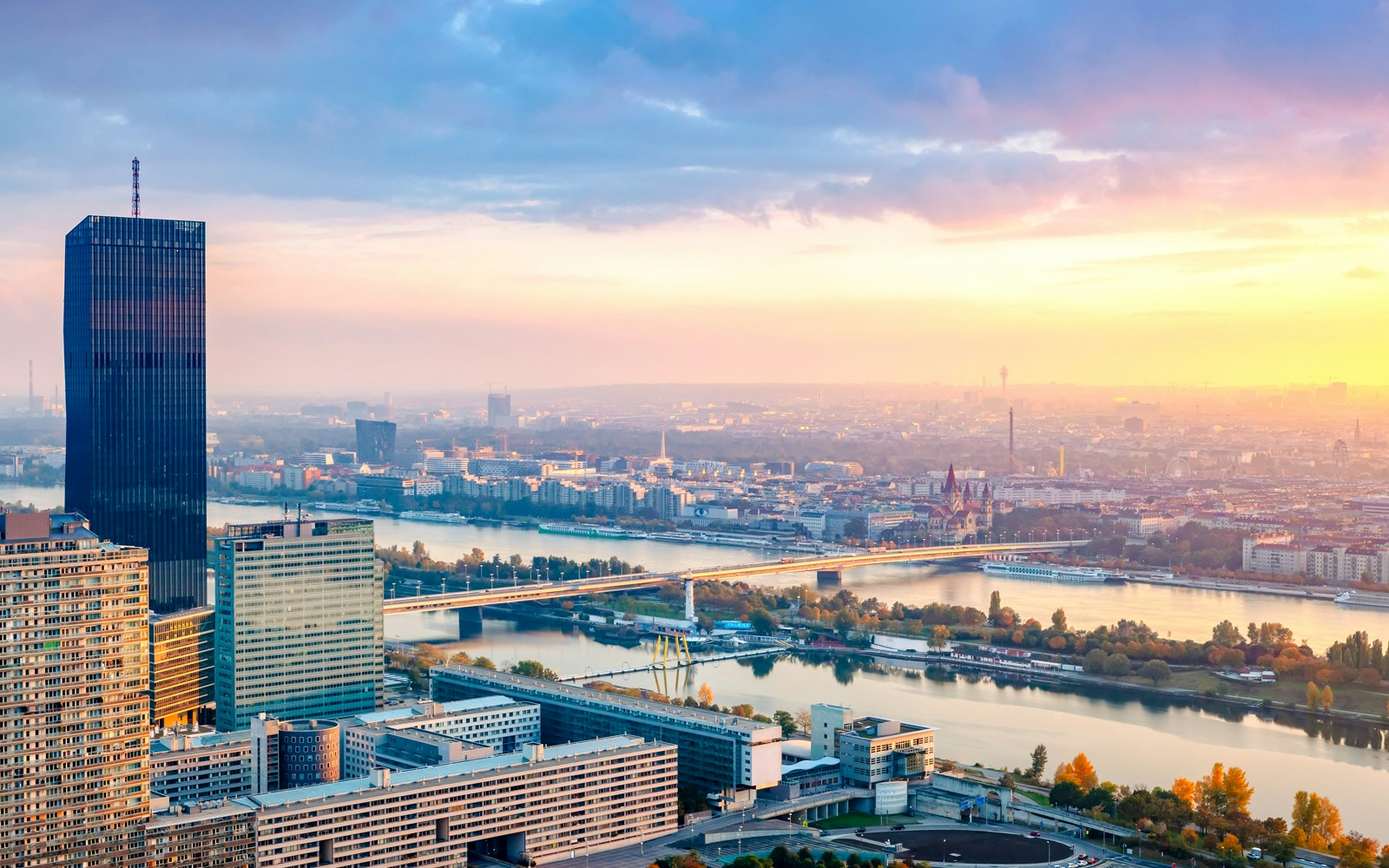 Danube Canal cruise at sunset with Vienna skyline in the background.