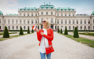 Woman holding a flag in front of Upper Belvedere Palace on a guided tour in Vienna.