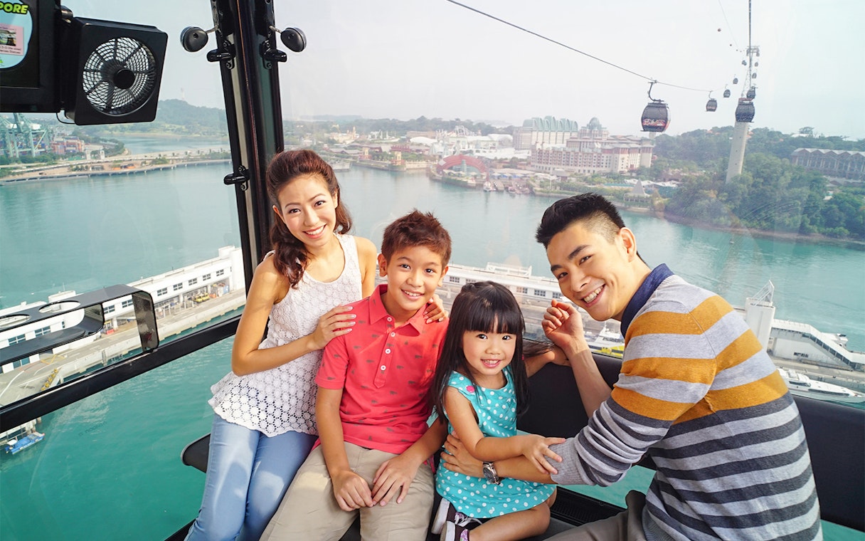 Family enjoying a cable car ride with views of Sentosa Island, Singapore.