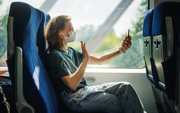 Person on train seater chair video calling through smartphone.