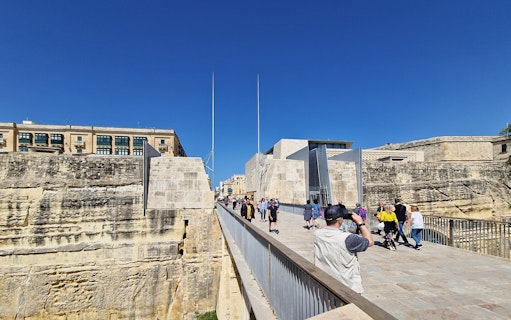 Visitors walking on a bridge towards Valletta's historic city gate during a food tour.