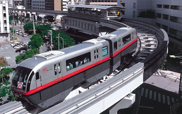 Okinawa Monorail train traveling through urban landscape in Naha, Japan.