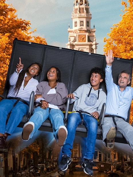 Tourists experiencing 5D ride at This Is Holland with Amsterdam tower in background.